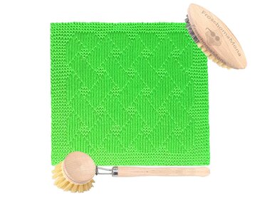 Grünes gestricktes Tuch mit Rautenmuster neben zwei Holzbürsten