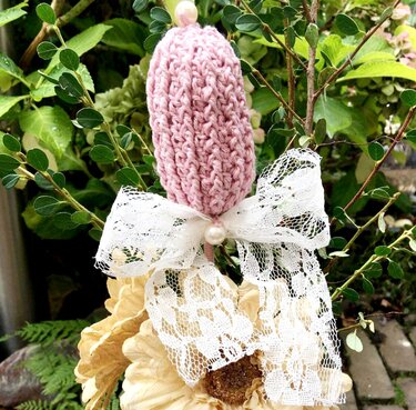 Schnell gehäkelte rosa Knospe mit Spitzen-Schleife und Perle an Zweig