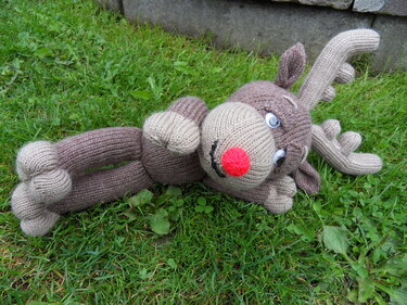 Gestricktes Rentier-Amigurumi mit roter Nase und Geweih auf grünem Rasen