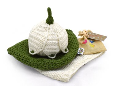 Gehäkeltes Neugeborenen-Set mit cremefarbener Mütze, grüner Unterlage, heller Decke und kleiner Geschenktasche