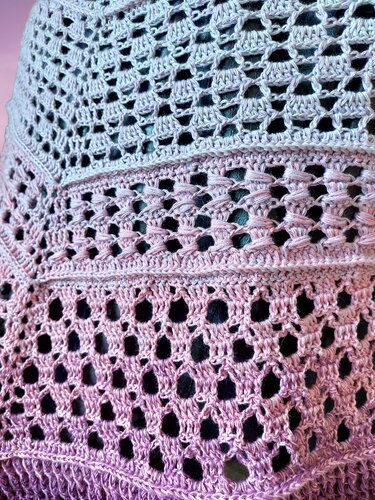 Detailed view of openwork and textured stitches on a lavender and pink gradient triangle crochet shawl.