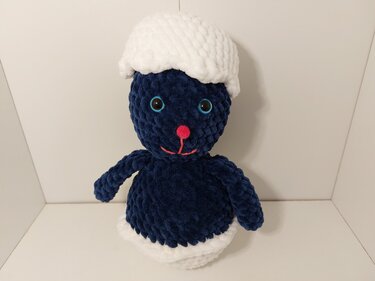 niedlicher dunkelblauer Amigurumi-Hase mit weißer Mütze und rosa Nase