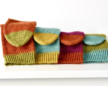 Vier gefaltete gestrickte Socken in leuchtenden Farben nebeneinander