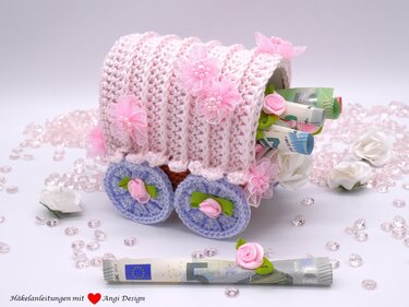 Gehäkelter Wagen als Geschenkverpackung mit aufgerollten Geldscheinen und Blumenverzierungen
