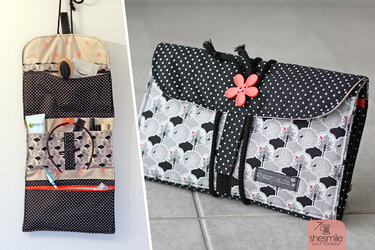 Aufrollbare Organizer‑Tasche offen hängend und geschlossen gefaltet; gemusterter Stoff mit Punkten und Baum‑Motiv; mehrere Innenfächer sichtbar.