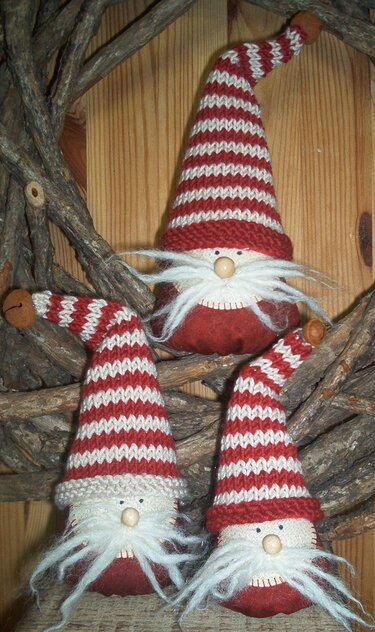 Drei DIY-Wichtel mit genähten Körpern, rot-weiß gestrickten Mützen, Holznasen und flauschigen Bärten