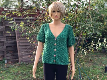Schaufensterpuppe mit grünem, gestricktem Cardigan mit kurzen Puffärmeln und sternförmigen Knöpfen