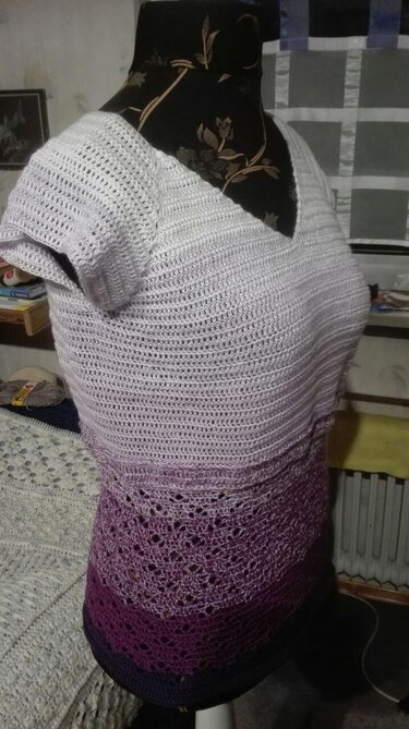 Mannequin trägt gehäkeltes Damen
Shirt mit V
Ausschnitt und Ombre
Farbverlauf, oberer Teil dicht gearbeitet, unterer Teil mit Lochmuster