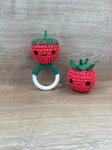 Zwei gehäkelte Erdbeeren: eine auf einem Holz-Greifring, eine als kleine Rassel