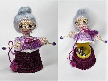 Gehäkelte Amigurumi-Oma mit Brille, strickt an einem lila Schal; ihr Rock enthält ein Nadelkissen mit bunten Stecknadeln.