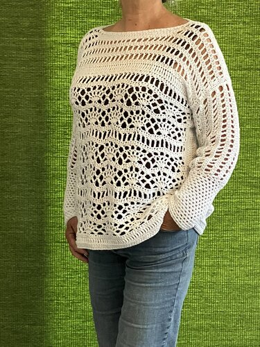 Weißer gehäkelter Pullover mit Lochmuster und weitem Ausschnitt, kombiniert mit Jeans
