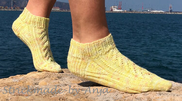 Nahaufnahme gelber gestrickter Knöchelsocken mit Rippenbund und Ajourstreifen