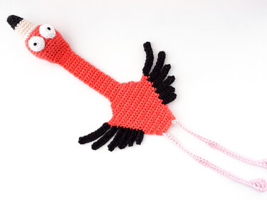 Coral crocheted flamingo bookmark with black wing accents and pink dangling cords.