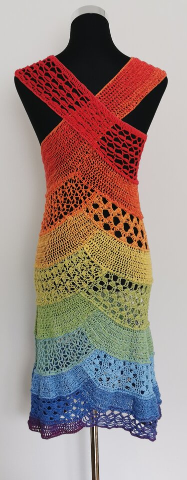 Langes gehäkeltes Damenkleid in Regenbogenfarben mit gekreuzten Trägern auf einer Schaufensterpuppe