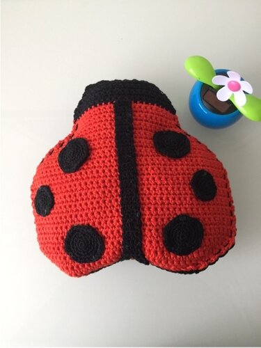 Gehäkeltes Marienkäfer-Kissen, rot mit schwarzen Punkten, auf hellem Untergrund