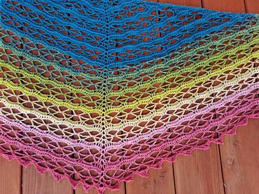 Gehäkeltes Dreieckstuch mit Farbverlauf und Lochmuster auf Holzuntergrund