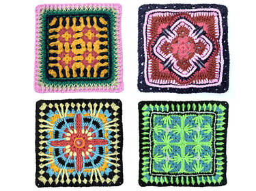 Vier gehäkelte Granny Squares in verschiedenen Farben und Mustern auf weißem Hintergrund