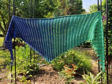 Gehäkeltes Dreieckstuch in Blau‑Grün mit Rippen‑ und Lochmuster sowie Bommelrand