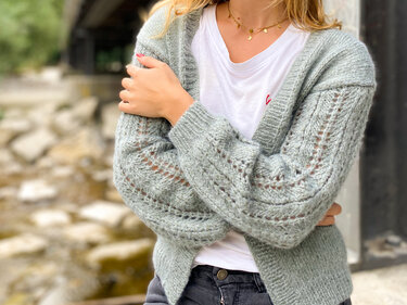 Hellgrüne Strickjacke mit Ajourmuster an den Ärmeln über weißem T-Shirt, Nahaufnahme