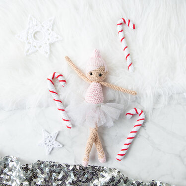 Gehäkelte Amigurumi‑Ballerina in rosa Tüll‑Tutu mit gehäkelten Zuckerstangen und Sternen auf hellem Hintergrund
