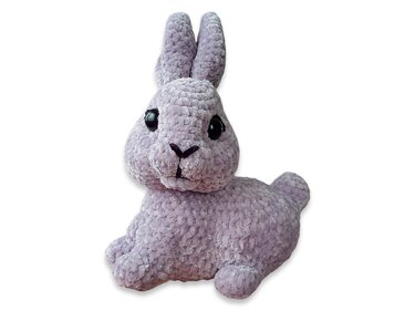 Light purple plush crocheted amigurumi rabbit with upright ears and large black eyes, sitting.