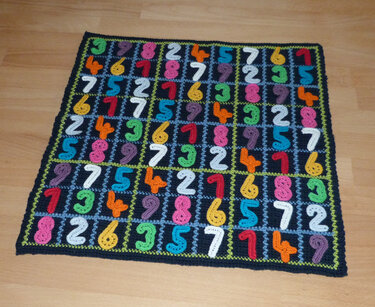Krabbeldecke aus gehäkelten Quadraten mit farbigen Zahlenapplikationen