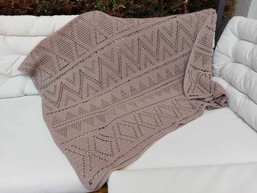 Puderrosa gehäkelte Decke mit Zickzack- und Rautenmuster auf weißem Sofa drapiert