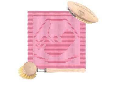 Quadratisches rosa Stricktuch mit stilisiertem Babykopf- und Herzmuster; zwei Holzbürsten daneben