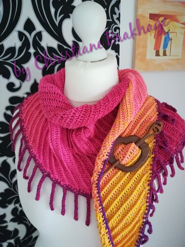 Gehäkeltes Dreieckstuch in Pink, Orange und Gelb mit lila Fransen und herzförmiger Holzbrosche auf einer Schaufensterpuppe