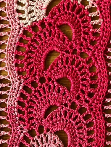 Häkelstoff in Hell- bis Dunkelrosa mit sich wiederholenden Fächermotiven