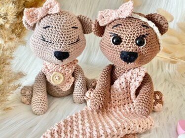 Zwei gehäkelte Amigurumi-Teddys mit rosa Schleifen und Tüchern