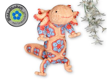 Crocheted axolotl amigurumi made from peach and blue African flower granny motifs, laid flat with visible limbs and tail