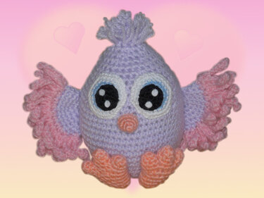 Gehäkelter Amigurumi-Vogel in Pastellfarben mit großen schwarzen Augen, rosa Flügeln und orangefarbenem Schnabel und Füßen