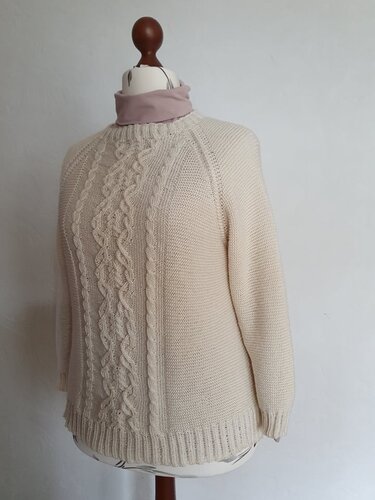 Beigefarbener gestrickter Pullover mit zentralem Zopfmuster auf einer Schneiderpuppe.