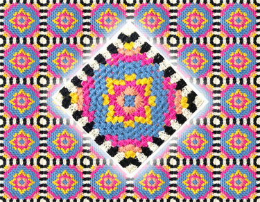 Gehäkelte Decke aus bunten Granny-Squares mit schwarz-weißem Streifenrand
