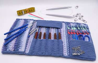 Gehäkeltes blau-lila Etui mit Häkelnadeln, Maschenmarkierern, Schere, Sicherheitsnadeln, Maßband und Rundstricknadeln.