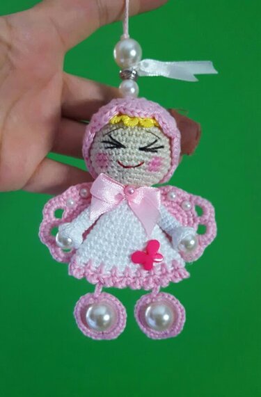 Gehäkelter Amigurumi-Engel in rosa und weiß mit Perlen, Schleife und gesticktem Gesicht an einer Aufhängeschnur