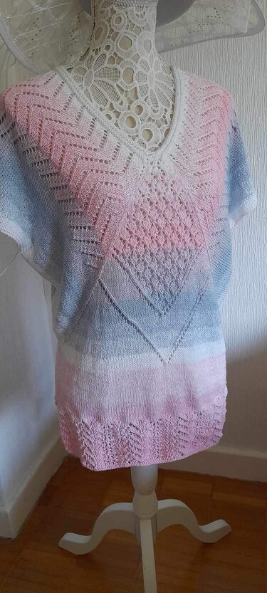 Gestrickte Damen-Tunika mit V-Ausschnitt auf Schneiderpuppe, Pastellverlauf Hellblau-Weiß-Rosé, Kurzarm, Lochmuster