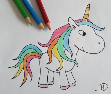 Ausgemaltes Einhorn mit Regenbogenmähne und drei Buntstiften auf weißem Papier