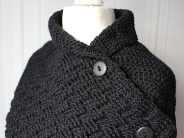 Black crocheted collar scarf with high collar and two dark buttons on a mannequin