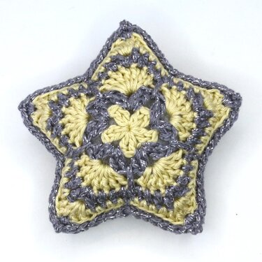 Gepolsterter gehäkelter Stern im African‑Flower‑Muster, gelb mit silbernem Rand