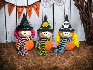 Drei gehäkelte Amigurumi-Hexen auf Kürbissen mit spitzen Hüten, Applikationen und gestreiften Schals für Halloween