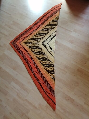Gestricktes Dreieckstuch in Orange und Schwarz mit wellenförmigem Muster auf hellem Boden