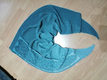Türkisfarbenes gestricktes Dreieckstuch mit Streifen und geometrischem Randmuster auf hellem Holz
