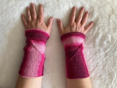 Paar Handstulpen aus kraus rechts gestricktem Garn in Pink mit diagonaler Naht an ausgestreckten Händen