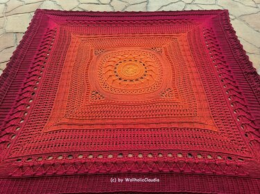 Quadratische gehäkelte Decke mit Ombré‑Verlauf von Orange zu Burgunderrot und zentralem Mandala