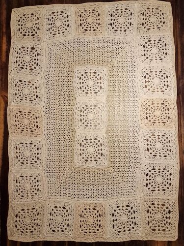 Naturfarbener gehäkelter Tischläufer aus verbundenen Granny-Quadraten auf dunklem Holz