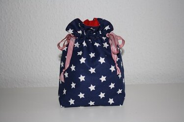 Selbstgenähte Utensilo-Tasche aus blauem Stoff mit weißen Sternen und rot-weiß gestreiftem Band.