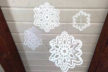Verschiedene ornamental gestaltete Schneeflocken mit feinen Ausschnitten, an transparenten Fäden befestigt