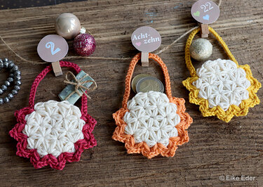 Close-up of three flower-style crocheted mini pouches with colored scalloped edges, suitable for an advent calendar.